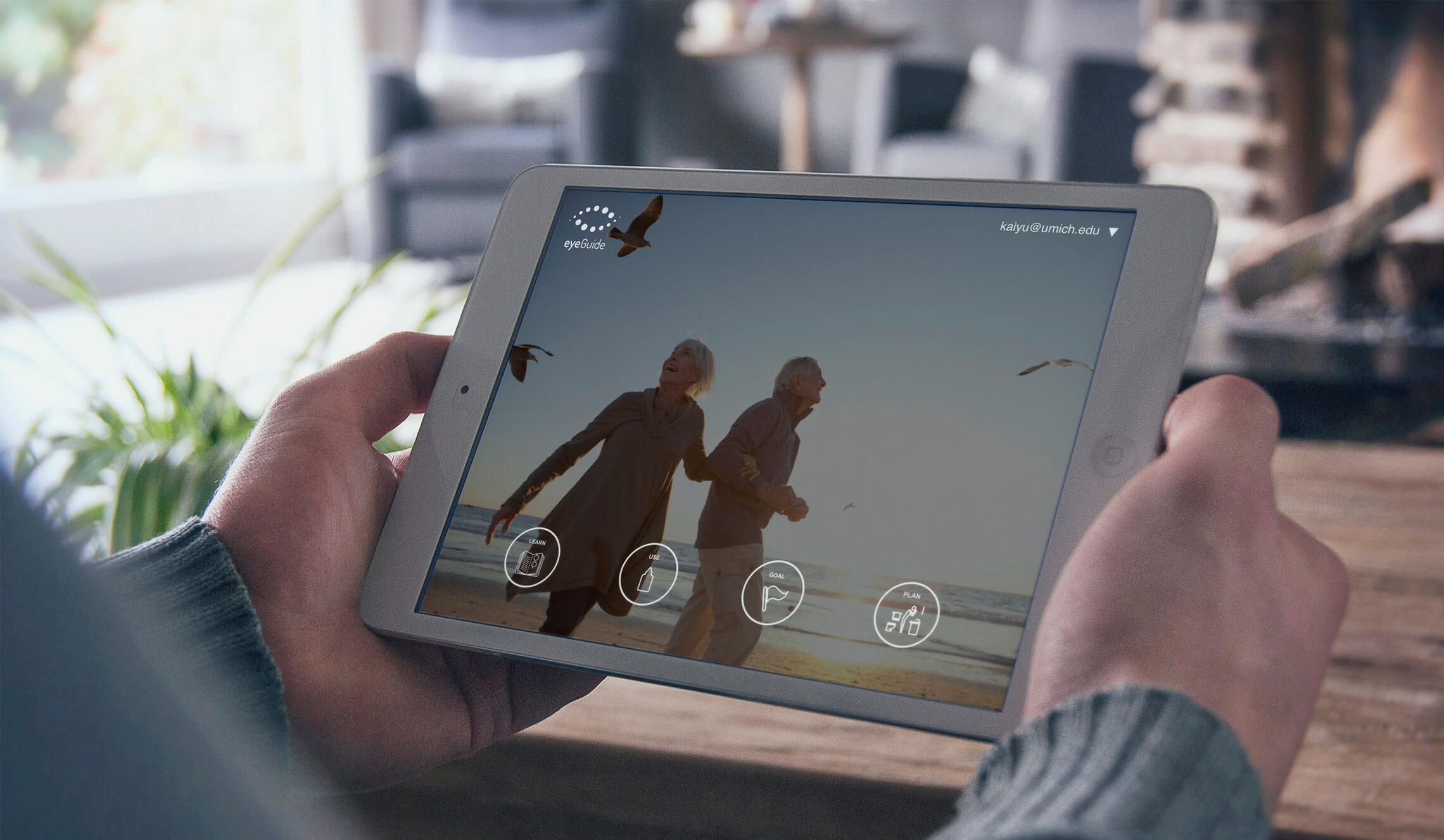 A man's hands holding an iPad displaying the eyeGuide application.
