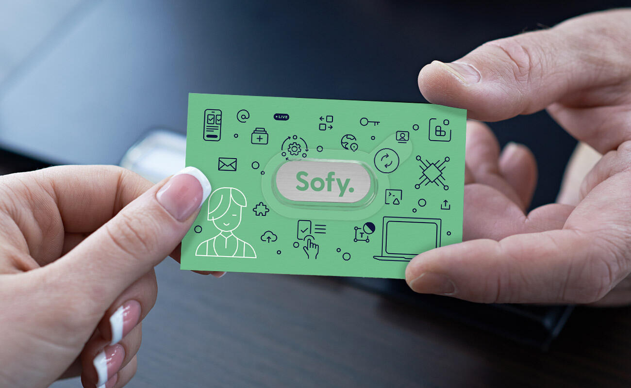 A webcam cover card is passed between two business people. The webcam cover has Sofy branding and packaging design.