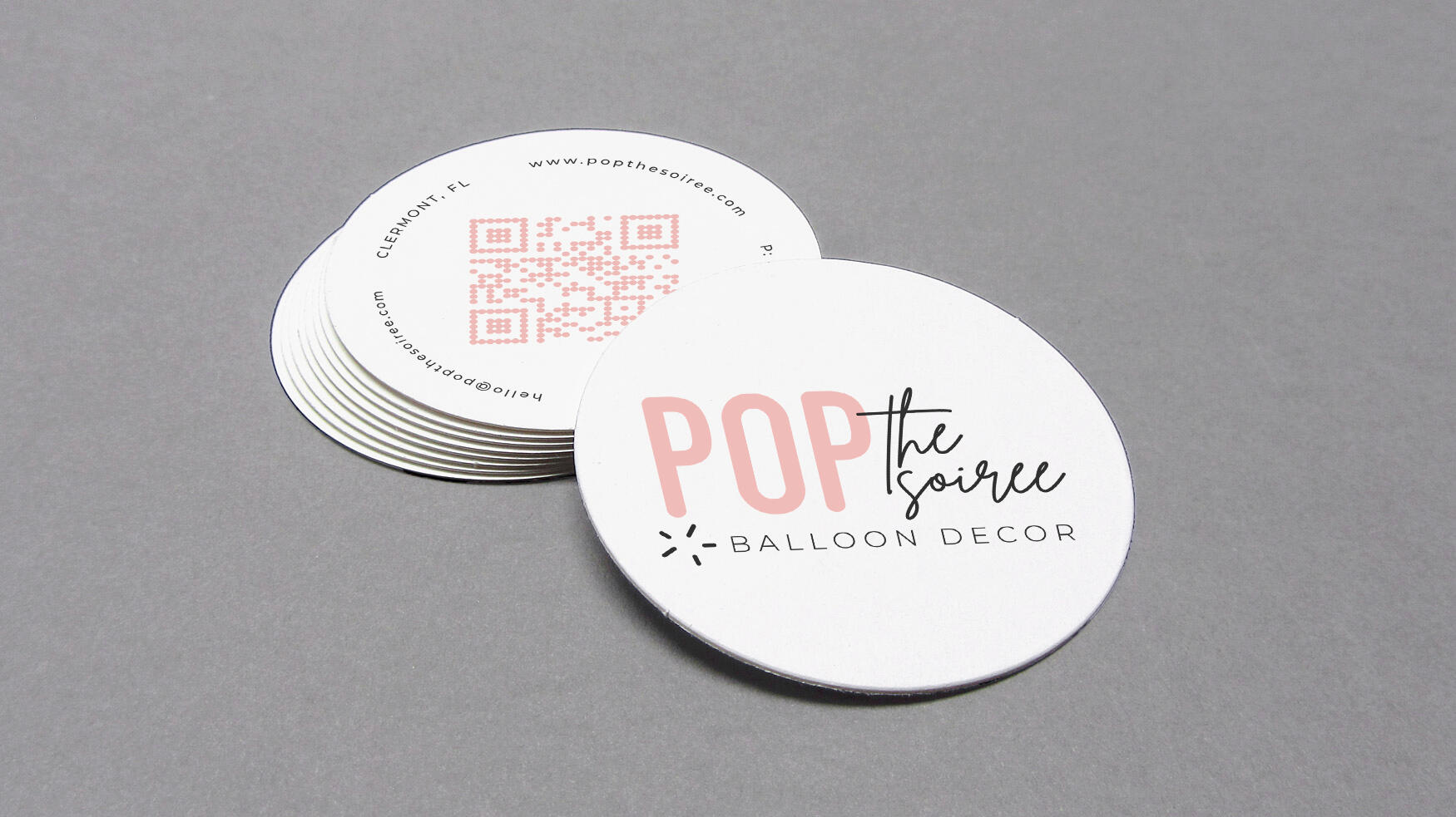 Front and back of a round business card design on a grey background.